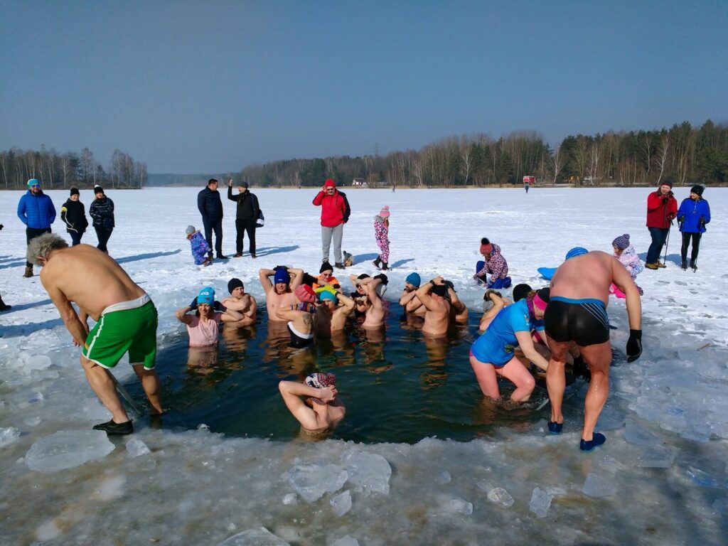 A group of winter swimmers immersed in a cut hole in a frozen lake