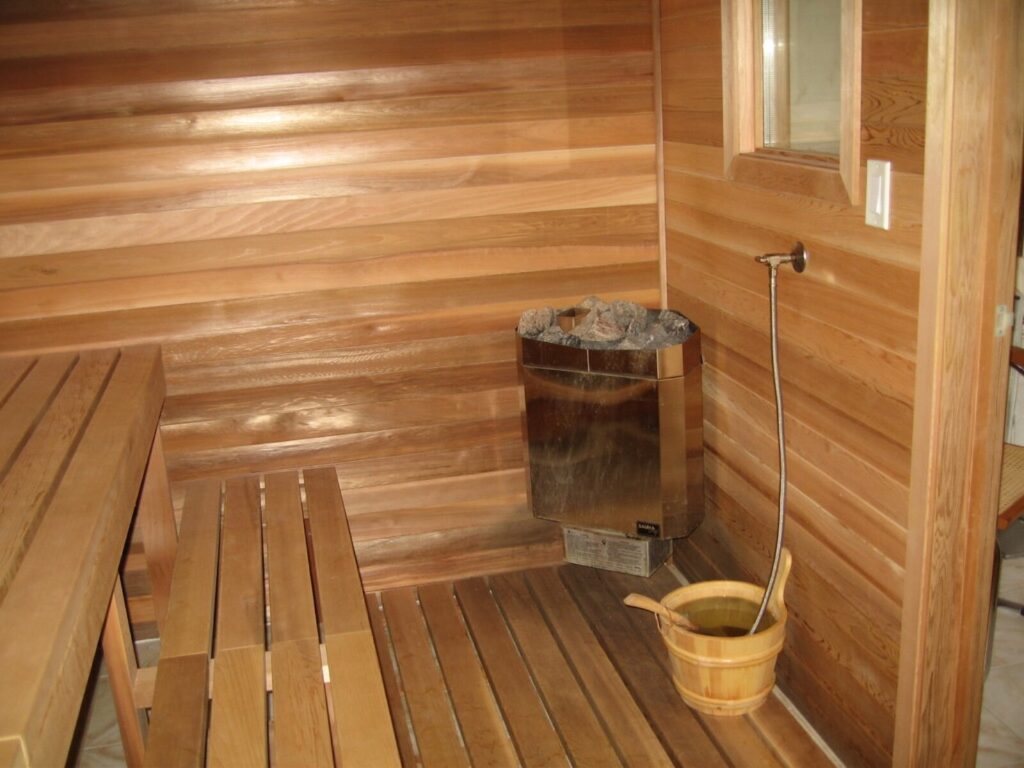 A home sauna with a cedar-lined interior, heater and water bucket