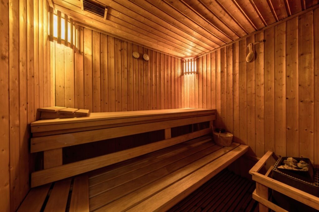 Warm timber-lined sauna interior with benches and a bucket